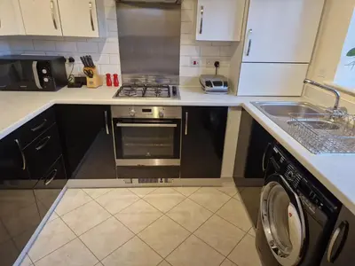 a kitchen with a stove and a sink and a dishwasher at Lovely and Cosy Double Room in Havering atte Bower
