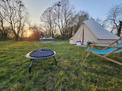 a tent and a table and a grill in a field at Readers Field Glamping in Great Sampford