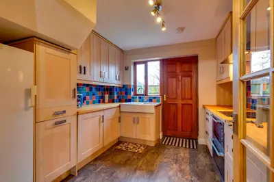 a kitchen with white cabinets and a wooden door at Pass the Keys Spacious Modern Home near River Cam Free Parking in Cambridge