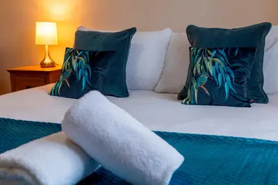 a bed with blue and green pillows at Pass the Keys Spacious Modern Home near River Cam Free Parking in Cambridge