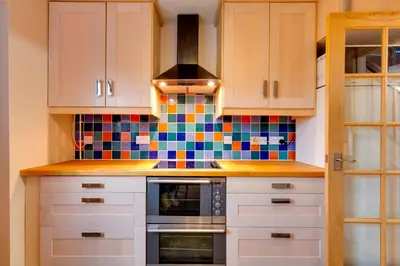 a kitchen with white cabinets and colorful tiles on the wall at Pass the Keys Spacious Modern Home near River Cam Free Parking in Cambridge