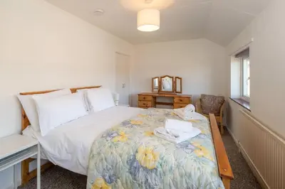 a bedroom with a bed with a flowery blanket at 6 Franklin Rd - Aldeburgh Coastal Cottages in Aldeburgh