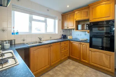 a kitchen with wooden cabinets and a large window at 6 Franklin Rd - Aldeburgh Coastal Cottages in Aldeburgh