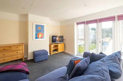 a living room with a blue couch and a tv at 6 Franklin Rd - Aldeburgh Coastal Cottages in Aldeburgh