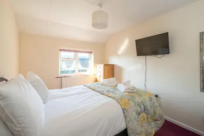 a bedroom with a bed with a tv on the wall at 6 Franklin Rd - Aldeburgh Coastal Cottages in Aldeburgh