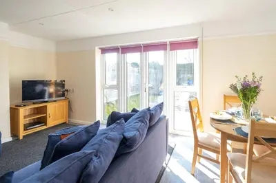 a living room with a couch and a tv and a table at 6 Franklin Rd - Aldeburgh Coastal Cottages in Aldeburgh