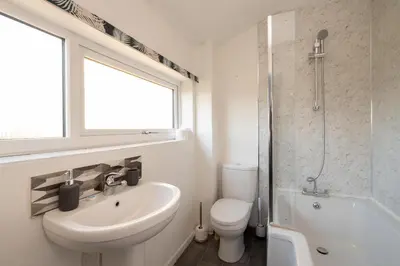 a bathroom with a sink and a toilet and a window at 51 The Plantation - Aldeburgh Coastal Cottages in Aldeburgh