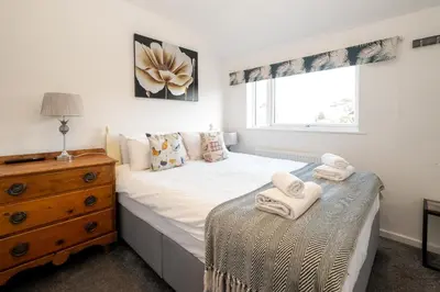 a bedroom with a bed and a dresser and a window at 51 The Plantation - Aldeburgh Coastal Cottages in Aldeburgh