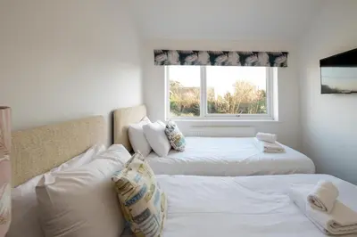 two beds in a room with a window at 51 The Plantation - Aldeburgh Coastal Cottages in Aldeburgh