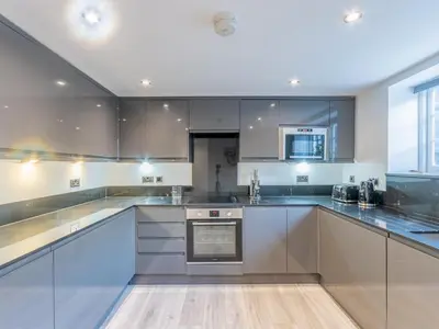 a large kitchen with white cabinets and appliances at 4-Bedroom Seafront House in Southend Sea Views - Pass the Keys in Southend-on-Sea