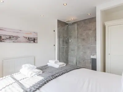 a white bedroom with a shower and towels on a bed at 4-Bedroom Seafront House in Southend Sea Views - Pass the Keys in Southend-on-Sea