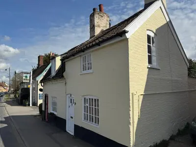 a white building with a chimney on a street at Cosy Little Cottage in Woodbridge