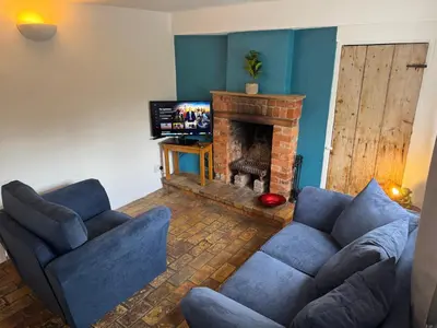 a living room with a couch and a fireplace at Cosy Little Cottage in Woodbridge