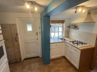 a kitchen with a blue wall and a stove top oven at Cosy Little Cottage in Woodbridge