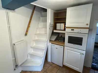 a small kitchen with a white refrigerator and a ladder at Cosy Little Cottage in Woodbridge