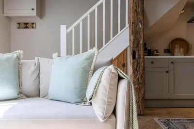a living room with a white couch with pillows at Ruperts Cottage in Coggeshall