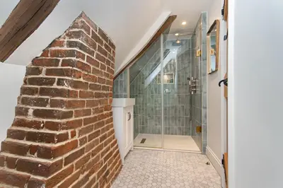 a bathroom with a brick wall and a shower at Ruperts Cottage in Coggeshall