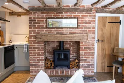 a brick fireplace with a stove in a kitchen at Ruperts Cottage in Coggeshall