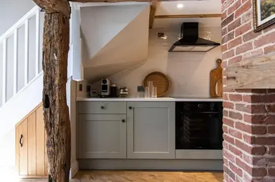 a kitchen with white cabinets and a sink in a room at Ruperts Cottage in Coggeshall