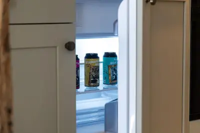 an open refrigerator door with cans of beer at Ruperts Cottage in Coggeshall