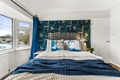 a bedroom with a large bed with a blue wall at Gorgeous Abode in Cambridge - Pet Friendly! in Cherry Hinton
