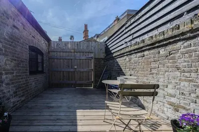 a patio with a table and chairs next to a brick wall at The Stables in Southend-on-Sea
