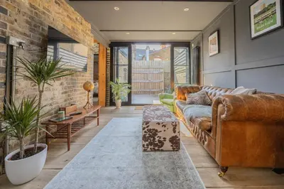 a living room with a couch and a brick wall at The Stables in Southend-on-Sea