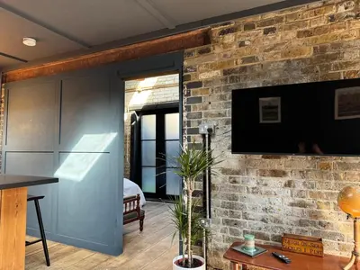 a living room with a brick wall with a flat screen tv at The Stables in Southend-on-Sea