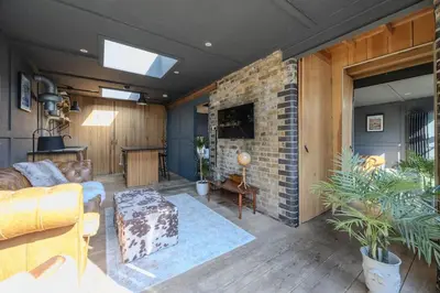 a living room with a couch and a brick wall at The Stables in Southend-on-Sea