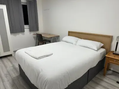 a bedroom with a large bed with a desk and a chair at Modern Stylish 4Bed 2 Bath in Pitsea, Basildon Essex 2 Free Carpark in Nevendon