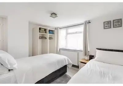 a white bedroom with two beds and a window at The Barack Nest Colchester in Colchester
