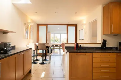 a kitchen with wooden cabinets and a table with chairs at Stylish 3-Bedroom Detached Home in Cambridge in Chesterton