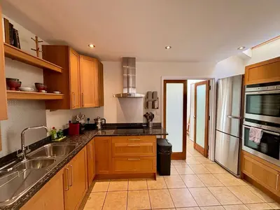 a kitchen with wooden cabinets and a stainless steel sink at Stylish 3-Bedroom Detached Home in Cambridge in Chesterton