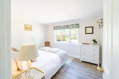 a white bedroom with a bed and a window at Marvellous secluded forest lodge - Stone Hall in Eyke