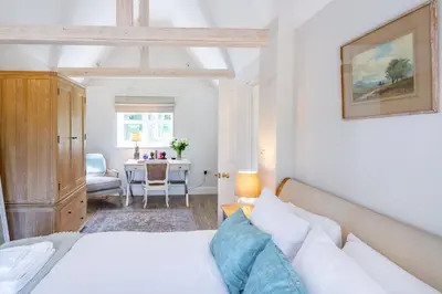 a bedroom with a bed and a table with a chair at Marvellous secluded forest lodge - Stone Hall in Eyke
