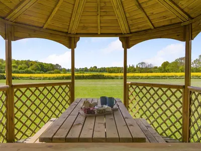 a wooden table on a gazebo with a view of a field at Cedar - Uk49525 in Saint Lawrence