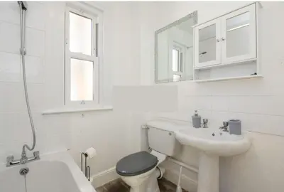 a white bathroom with a toilet and a sink at The Harwich Hideaway in Harwich