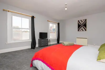 a bedroom with a large bed with a red blanket at The Harwich Hideaway in Harwich