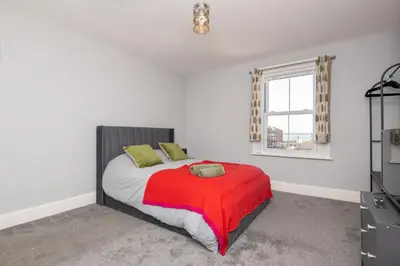 a bedroom with a bed with a red blanket and a window at The Harwich Hideaway in Harwich