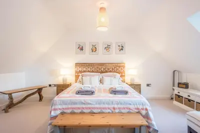 a bedroom with a large bed and a wooden table at 8 Oaks Court, Thorpeness in Thorpeness