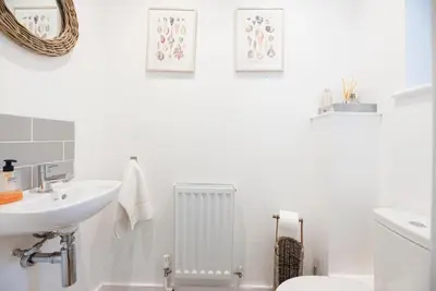 a white bathroom with a sink and a toilet at 8 Oaks Court, Thorpeness in Thorpeness