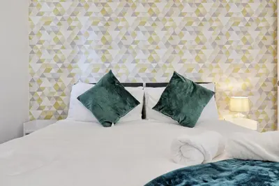 a bedroom with a white bed with green pillows at Spacious Colchester Home with Off-Street Parking for 4 cars in Colchester