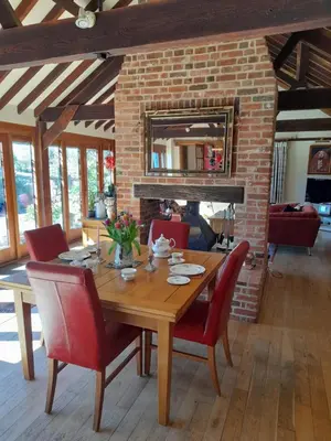 a dining room with a wooden table and red chairs at Wisteria Barn in Harleston