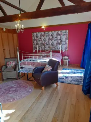 a bedroom with a bed and a chair at Wisteria Barn in Harleston