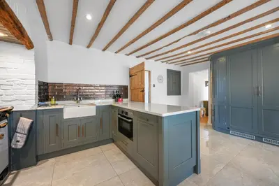 a large kitchen with blue cabinets and a ceiling at Bakers Cottage, Blackmore End in Gosfield