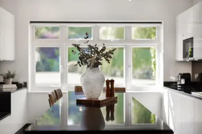 a vase with flowers sitting on a table in a kitchen at Merry Lakes - Luxury Lakeside Escape with Pool - Just 30 Minutes from London in Hutton