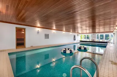 a large swimming pool with two chairs in it at Merry Lakes - Luxury Lakeside Escape with Pool - Just 30 Minutes from London in Hutton