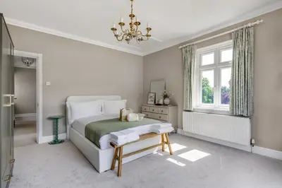 a white bedroom with a bed and a chandelier at Merry Lakes - Luxury Lakeside Escape with Pool - Just 30 Minutes from London in Hutton