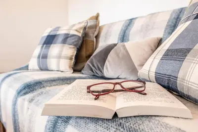 a book and a pair of glasses sitting on a couch at The Old Dairy, Cookley in Cookley
