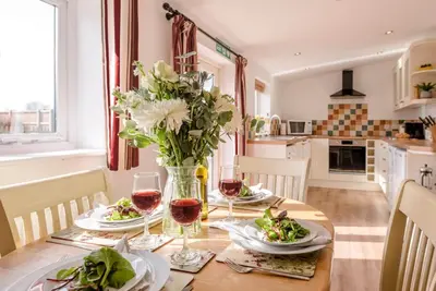a dining room table with a vase of flowers and wine glasses at The Old Dairy, Cookley in Cookley